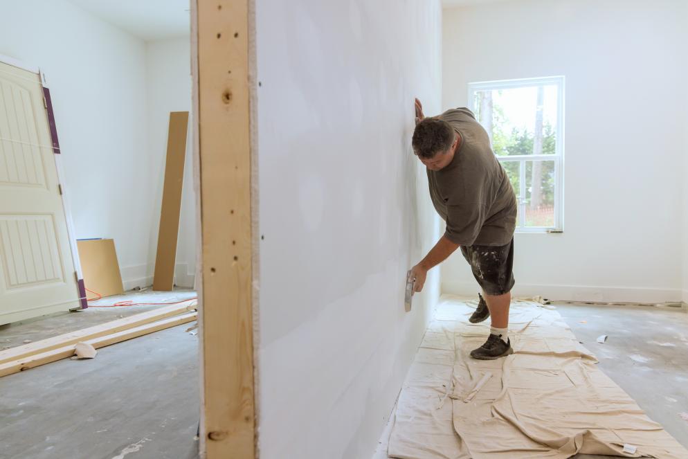 Technician cutting drywall panel for wall repair