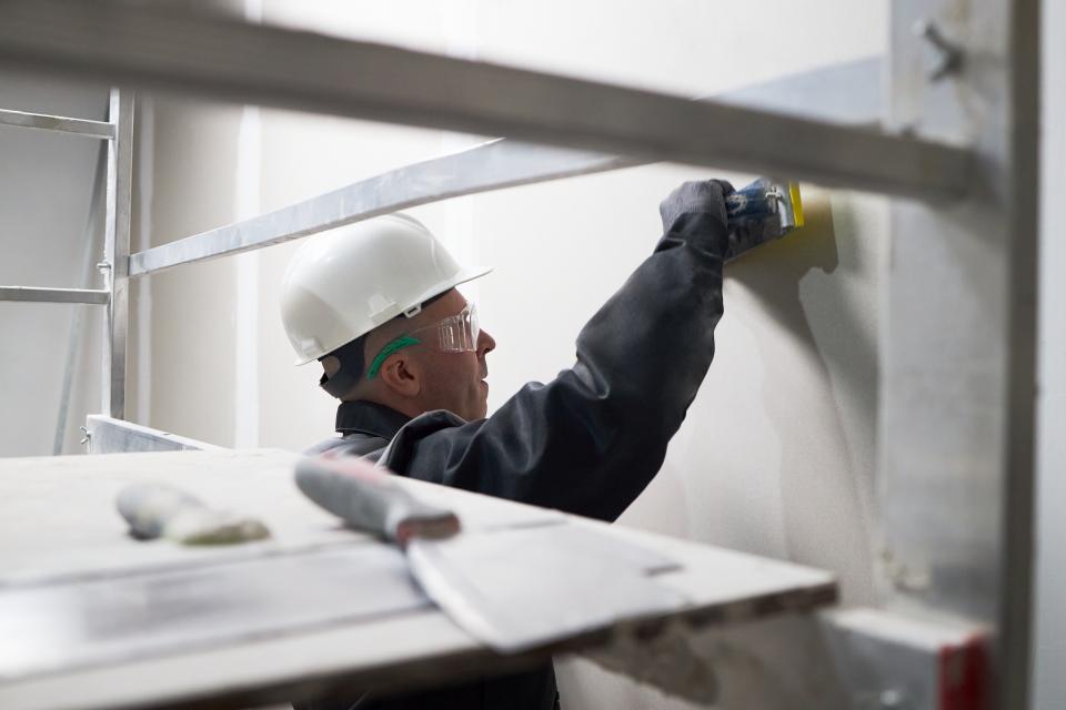 Drywall technician repairing interior wall in home