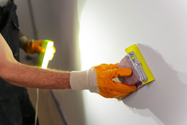 Worker repairing drywall with plaster and tools