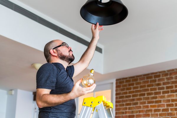 Electrician installing ceiling light fixture in modern home