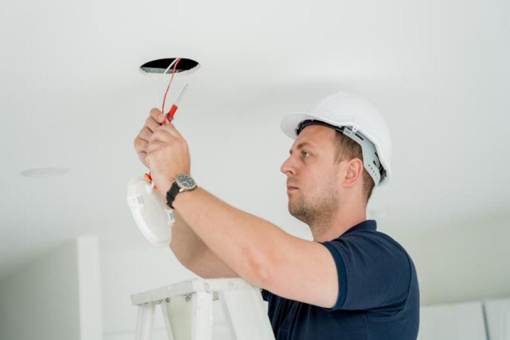 Electrician installing ceiling light fixture in a residential home